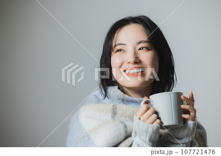 温かい飲み物を飲む女性 107721476