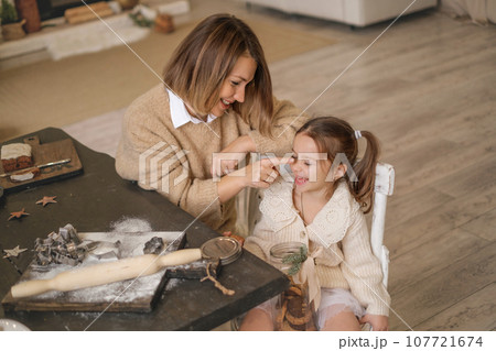 Mother and child are sitting at a table with ginger cookies cooked together 107721674
