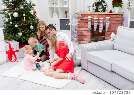 Family spends Christmas together by fireplace and tree Family spends Christmas together by fireplace and tree 107722788