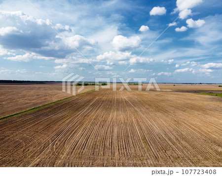 Beautiful cloudy sky over plowed farm fields. Agricultural landscape. 107723408