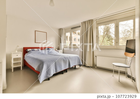 a bedroom with a bed, desk and chair in front of the window that looks out to the garden outside a bedroom with a bed, desk and chair in front of the window that looks out to the garden outside 107723929
