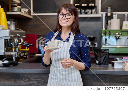 Portrait of female small business owner wearing apron near coffee shop counter Portrait of female small business owner wearing apron near coffee shop counter 107725807