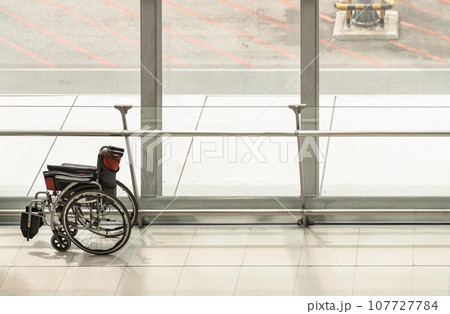Side view of Empty black wheelchair near the glass walls. 107727784