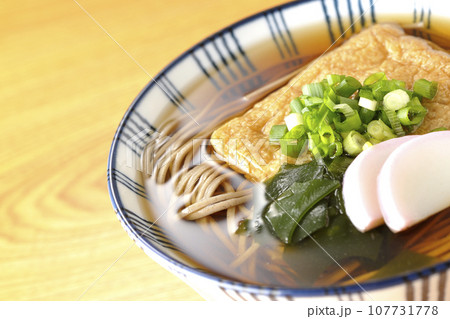 油揚げ、かまぼこ、ワカメ、葱が乗ったきつね蕎麦 油揚げ、かまぼこ、ワカメ、葱が乗ったきつね蕎麦 107731778