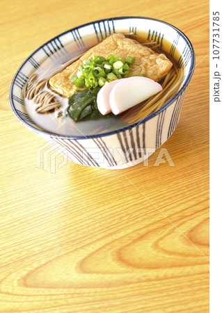油揚げ、かまぼこ、ワカメ、葱が乗ったきつね蕎麦 107731785