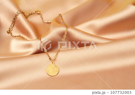 Golden necklace with pendant on silk background 107732003