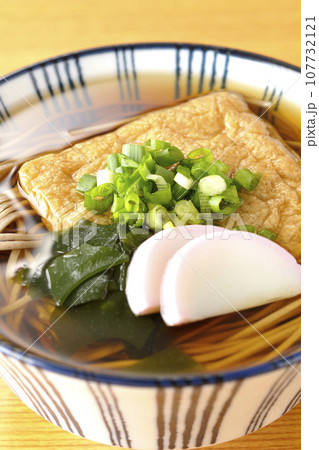 油揚げ、かまぼこ、ワカメ、葱が乗ったきつね蕎麦 107732121