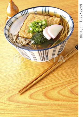 油揚げ、かまぼこ、ワカメ、葱が乗ったきつね蕎麦と瓢箪型の唐辛子入れ 油揚げ、かまぼこ、ワカメ、葱が乗ったきつね蕎麦と瓢箪型の唐辛子入れ 107732249