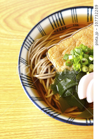 油揚げ、かまぼこ、ワカメ、葱が乗ったきつね蕎麦を俯瞰で撮影 油揚げ、かまぼこ、ワカメ、葱が乗ったきつね蕎麦を俯瞰で撮影 107732289