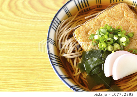 油揚げ、かまぼこ、ワカメ、葱が乗ったきつね蕎麦を俯瞰で撮影 油揚げ、かまぼこ、ワカメ、葱が乗ったきつね蕎麦を俯瞰で撮影 107732292