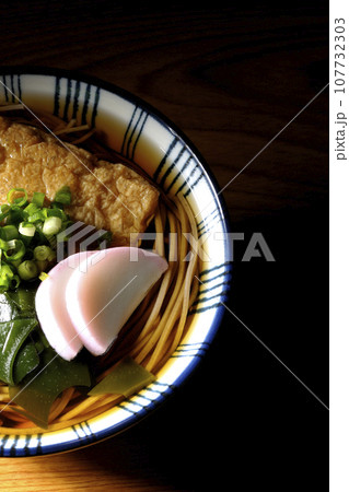 油揚げ、かまぼこ、ワカメ、葱が乗ったきつね蕎麦を俯瞰で撮影 油揚げ、かまぼこ、ワカメ、葱が乗ったきつね蕎麦を俯瞰で撮影 107732303