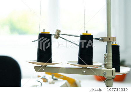 Thread bobbin on overlock sewing machine close up 107732339