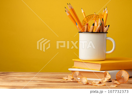 Metal cup with sharp pencils and pencil shavings on wooden desk 107732373