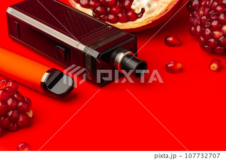 Electronic cigarette with pomegranate flavor on red background 107732707