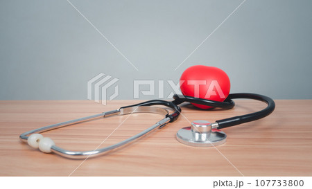 Red heart with headphones on a wooden table background. Medical and healthcare concepts. Red heart with headphones on a wooden table background. Medical and healthcare concepts. 107733800