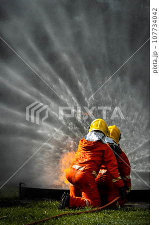Firefighter Concept. Fireman using water and extinguisher to fighting with fire flame. 107734042