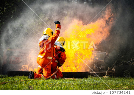 Firefighter Concept. Fireman using water and extinguisher to fighting with fire flame. 107734141