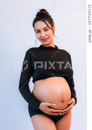 Pregnant belly. Woman standing and touching her naked big belly.  107734315