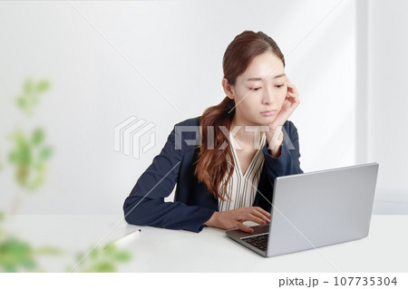 問い合わせのトラブルや仕事の生産性低下。オフィスで働く女性が悩みを抱える。白いオフィスの背景 問い合わせのトラブルや仕事の生産性低下。オフィスで働く女性が悩みを抱える。白いオフィスの背景 107735304