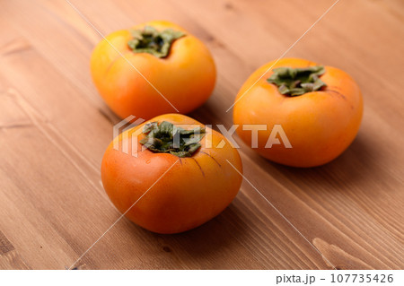 とっても甘い秋の味覚 柿 フルーツ （木目バック）柿の実 107735426