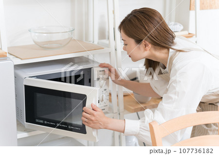 電子レンジを使う若い女性 電子レンジを使う若い女性 107736182