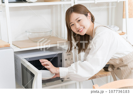 電子レンジを使う若い女性 電子レンジを使う若い女性 107736183