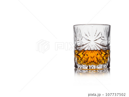 Scotch whiskey in crystal elegant glass on white background with reflection. 107737502