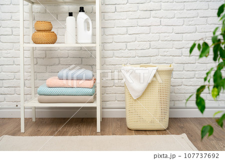 Beige plastic basket for laundry in a room Beige plastic basket for laundry in a room 107737692