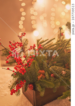 Floral arrangement in a wooden box with live spruce and ilex branches for decorating the house for the Christmas holidays.Christmas wooden box with fir branches for the holiday. The new year Floral arrangement in a wooden box with live spruce and ilex branches for decorating the house for the Christmas holidays.Christmas wooden box with fir branches for the holiday. The new year 107739513