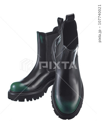 Beautiful pair of high demi-season boots made of black leather with a green spout, with a massive sole, isolated on a white background. Beautiful pair of high demi-season boots made of black leather with a green spout, with a massive sole, isolated on a white background. 107740021