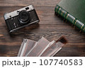 Vintage film camera, film and photo album on a dark wooden table. Top view 107740583