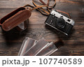 Vintage film camera with leather case and photographic film on dark wooden table. The view from the 107740589