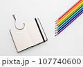 Clean notepad and rainbow color pencils in the shape of an arrow on a white background top view 107740600