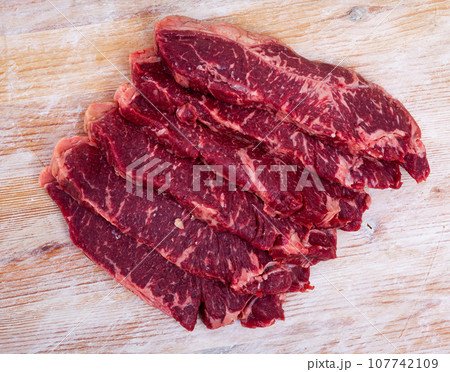 Uncooked beef fillet with parsley and garlic on table Uncooked beef fillet with parsley and garlic on table 107742109