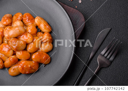 Delicious canned beans in a tomato in a round ceramic plate Delicious canned beans in a tomato in a round ceramic plate 107742142