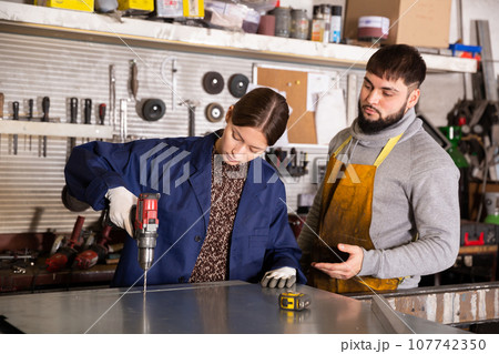 Woman working with metal sheet and using electric drill Woman working with metal sheet and using electric drill 107742350