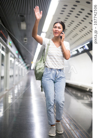 Woman talking on phone in subway station Woman talking on phone in subway station 107742506