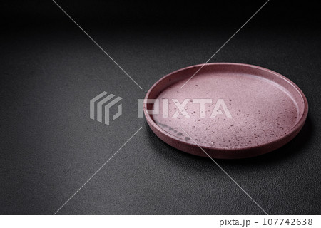 Empty ceramic plate on a dark textured background 107742638