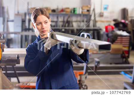 Workwoman inspecting steel stocks in workshop 107742769