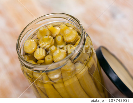 Glass jar with marinated okra on table 107742952