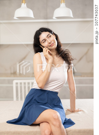 Young woman talking on phone in kitchen 107743037