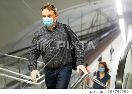 Man in disposable mask climbing stairs 107743590
