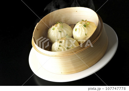 蒸籠で蒸された熱々小籠包を黒背景で撮影 107747778