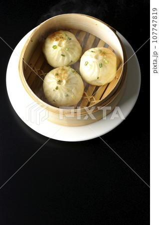 蒸籠で蒸された熱々小籠包を黒背景で俯瞰撮影 107747819