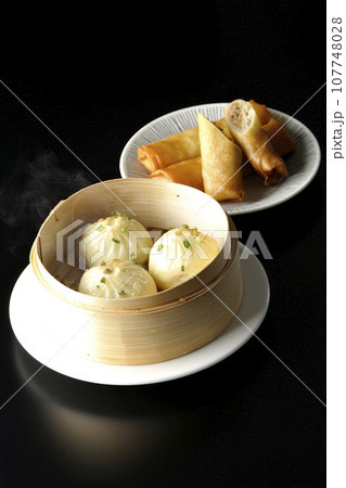 蒸籠に入っている熱々小籠包と揚げ春巻き 107748028