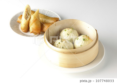 蒸籠に入っている熱々小籠包と揚げ春巻き 107748033
