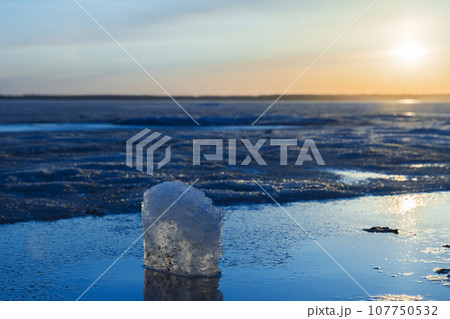 Winter landscape with frozen lake. Ice cube lays in a sunlight 107750532