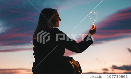 silhouette of Girl with Heart symbol in the sky 107750668