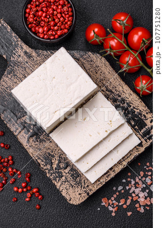 Delicious fresh ricotta cheese cut into slices with vegetables, salt and spices 107751280