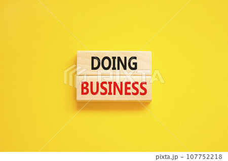 Doing business symbol. Concept words Doing business on beautiful wooden block. Beautiful yellow table yellow background. Business, motivational Doing business concept. Copy space. 107752218